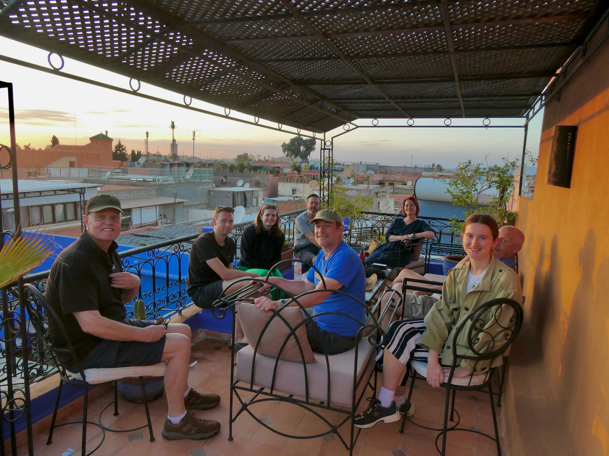 A group of travellers on a roof terrace in Marrakech at sunset.