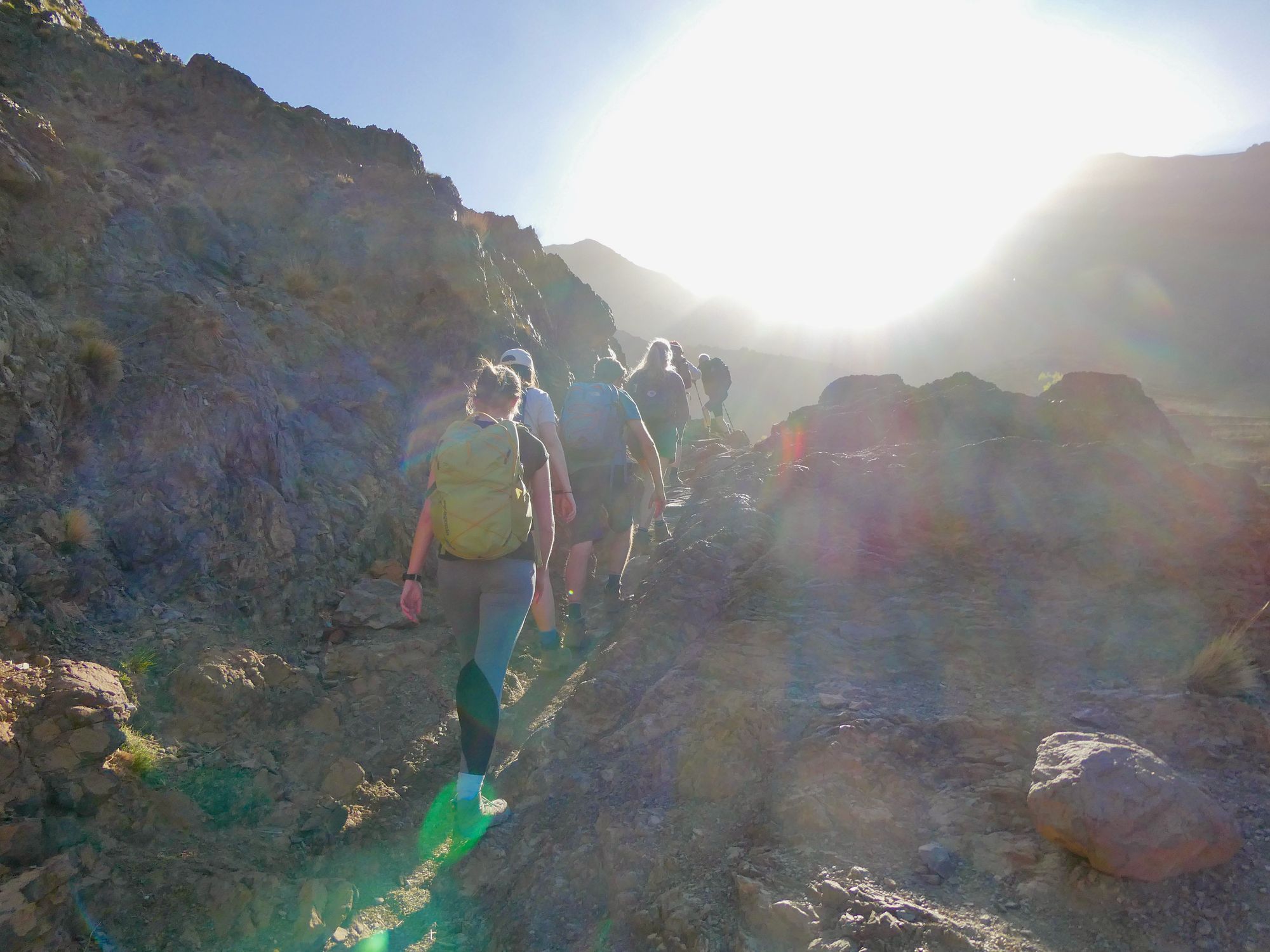 A light flare above a group of hikers as the sun comes over the Atlas Mountains.