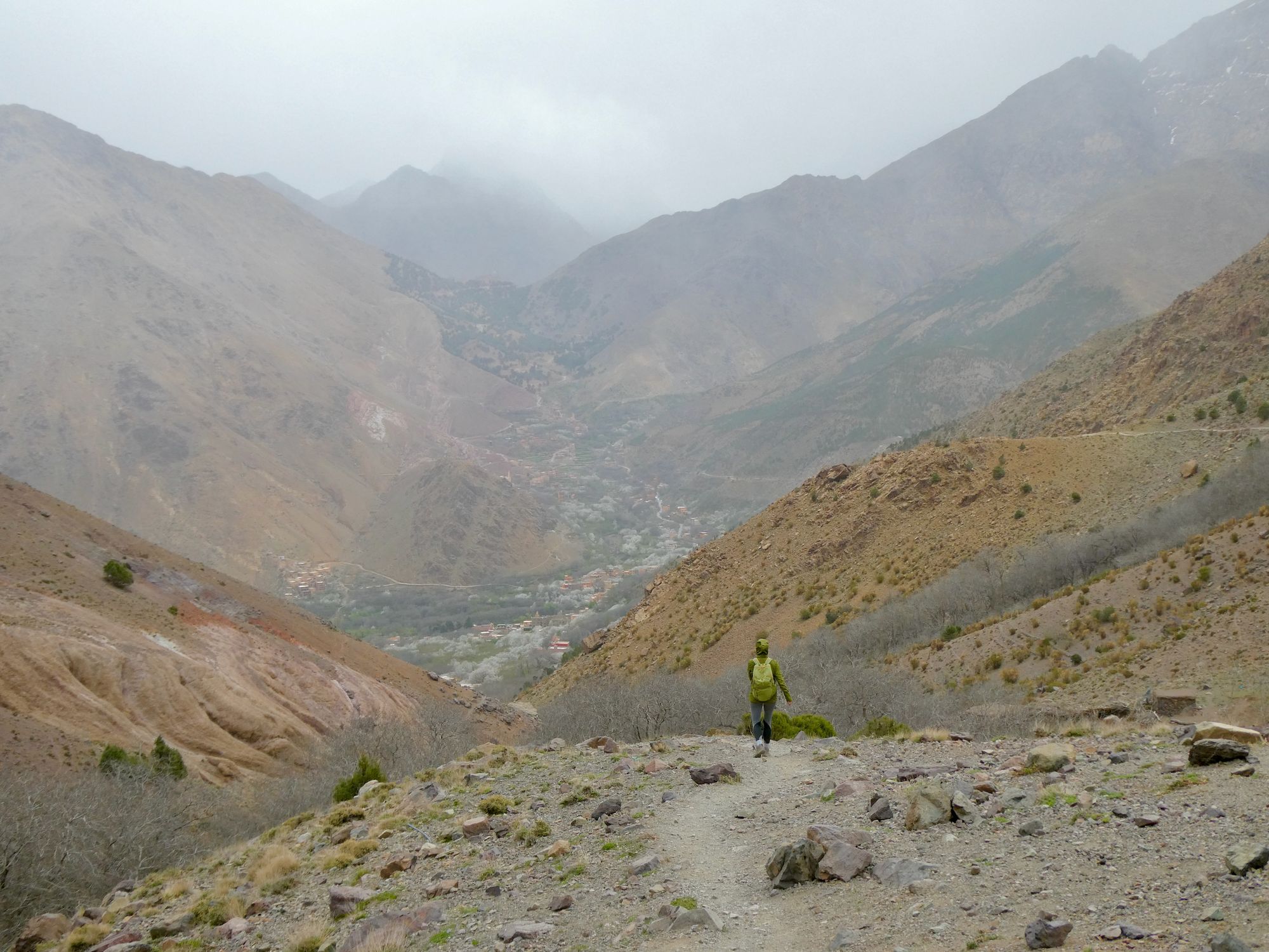 A hiker descending a trail in the clouds and rain in the Atlas Mountains.