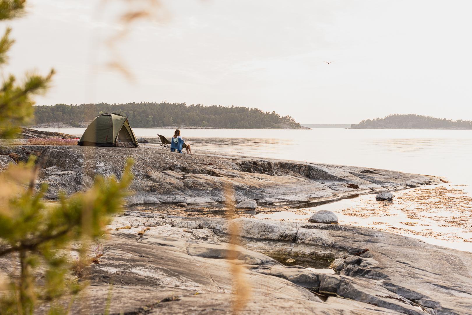 A sea kayaker and their tent, perched on a rocky outcrop overlooking the Baltic Sea. Photo: The Kayak Trail