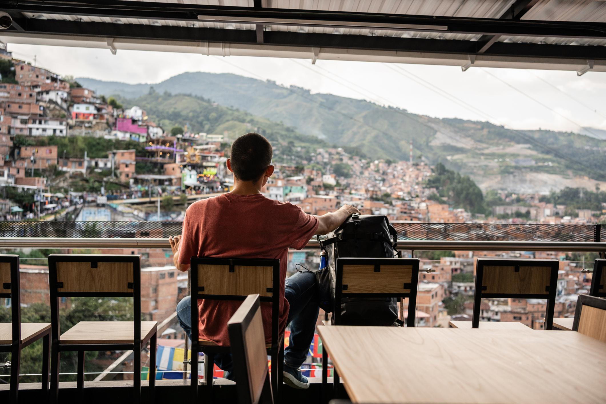 A man looking out over Medellín, with the crowds of Comuna 13 in the distance. Photo: Getty