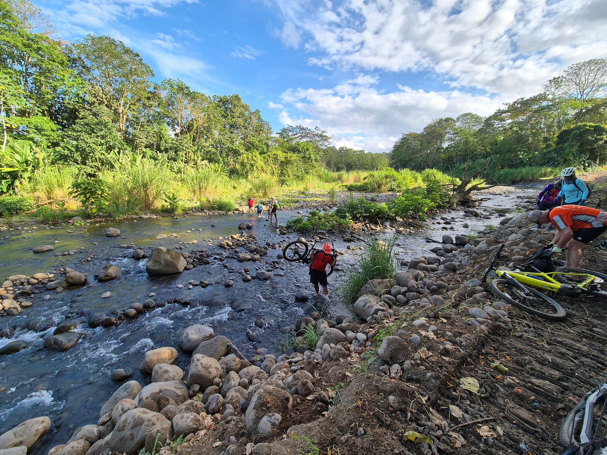 Cyclists carrying their bikes through a river in Costa Rica.