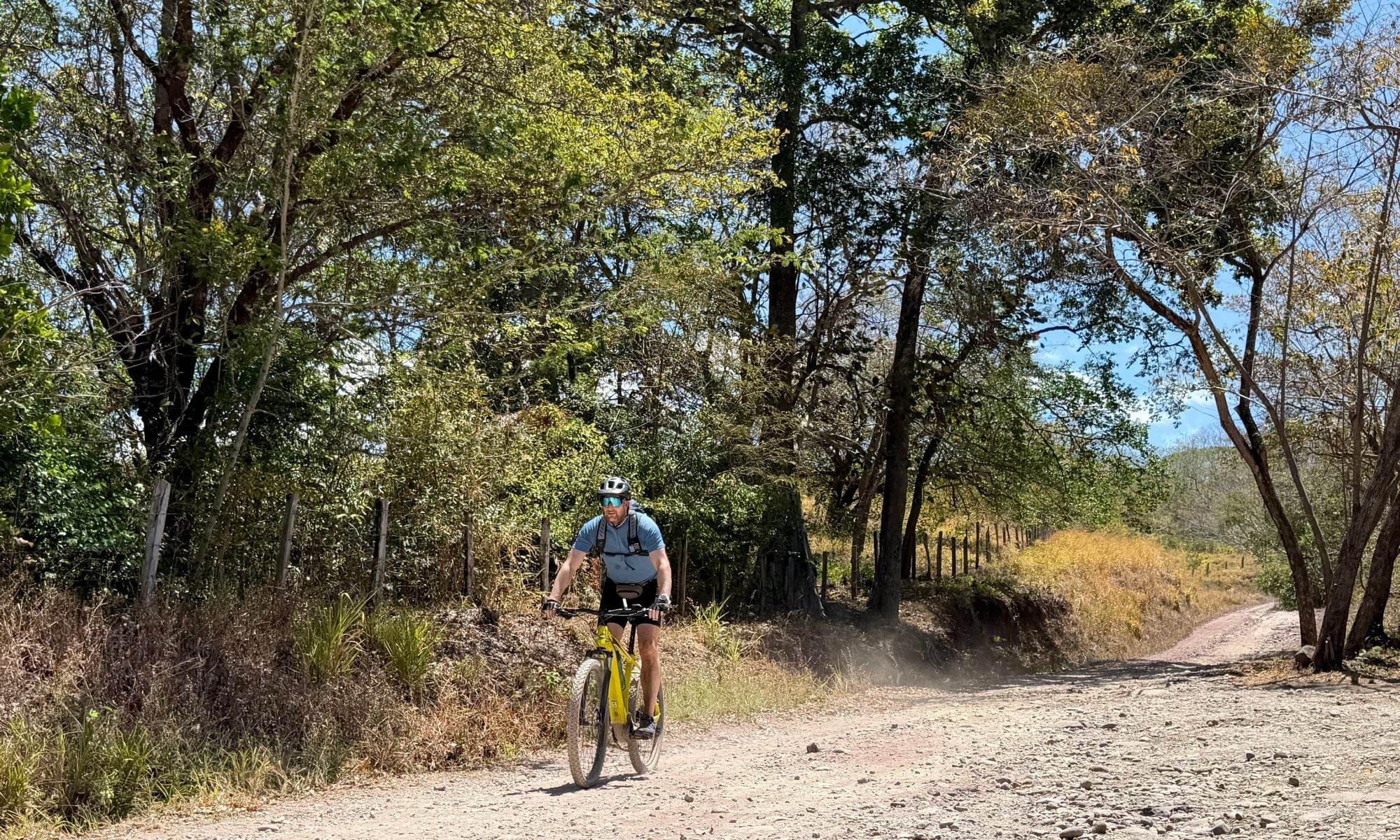 Man on a bike cycling on a gravel road in Costa Rica.