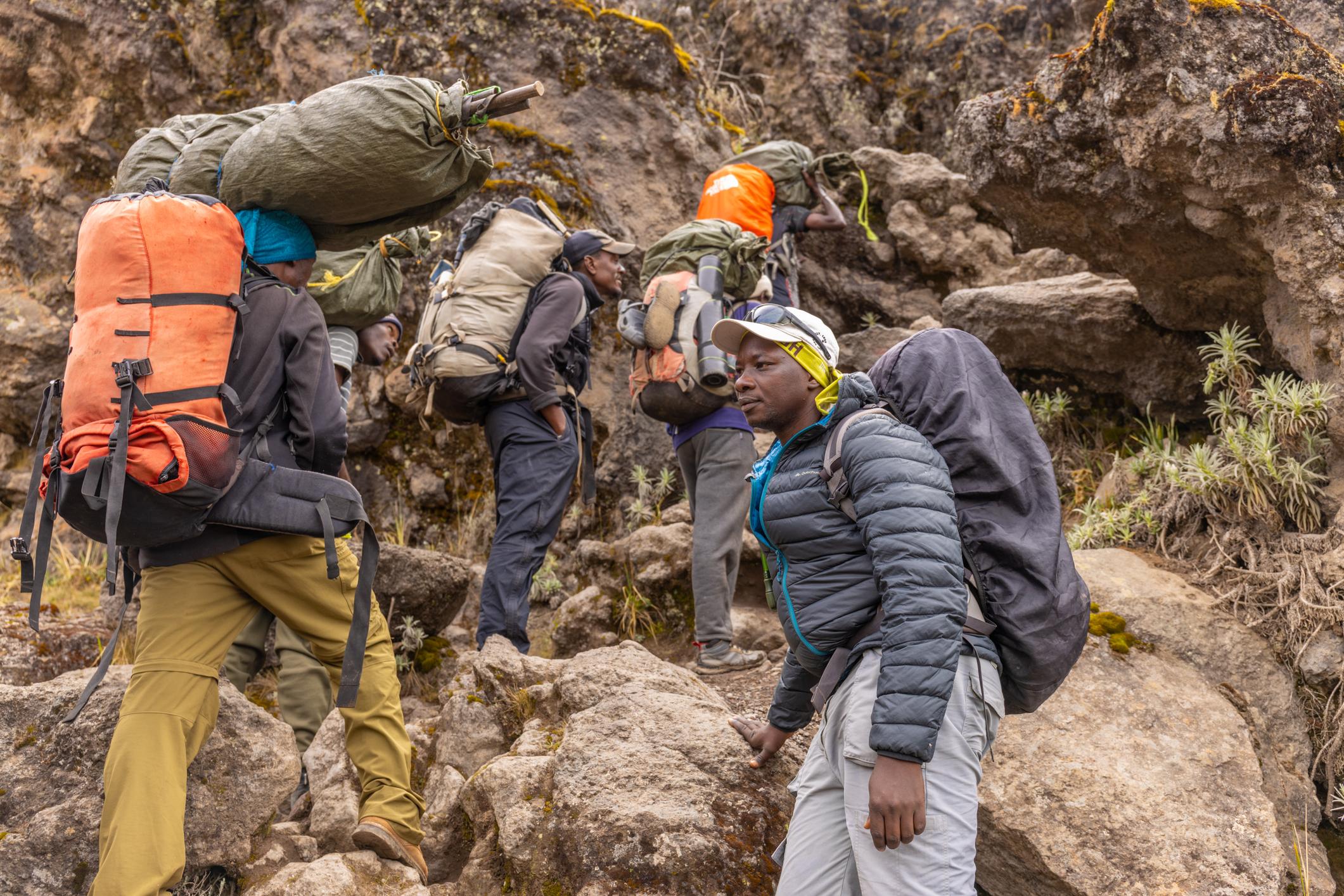 A lead guide with porters carrying gear up the mountain on Mount Kilimanjaro, Tanzania. Photo: Getty