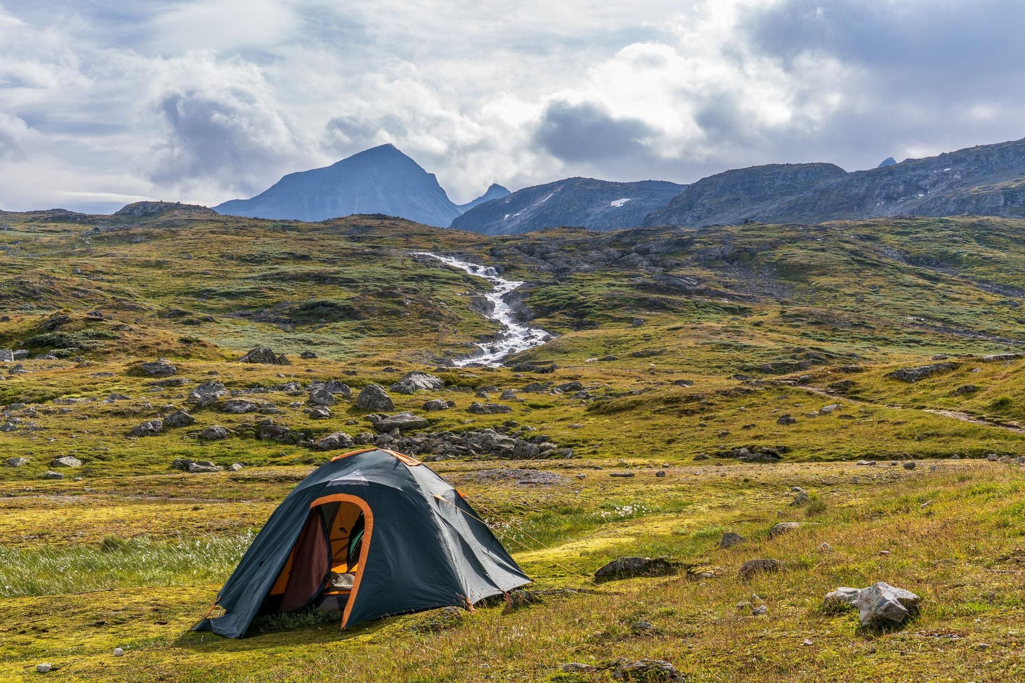 A grey and orange tent is pitched in the Norwegian tundra, on the Sognefjellet Plateau. Photo: Getty