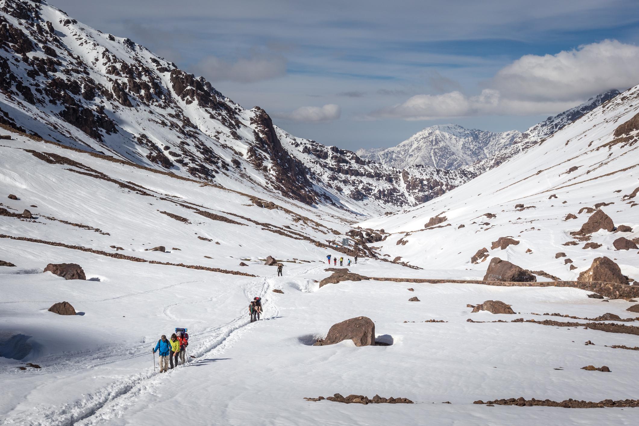 A group of hikers trekking into a valley in the snow, deep in the Atlas Mountains in Morroco. Photo: Getty